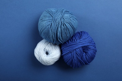 Photo of Soft woolen yarns on blue background, flat lay