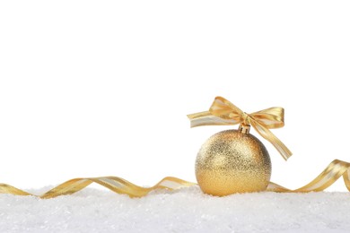 Photo of Beautiful golden Christmas ball with bow and ribbon on snow against white background