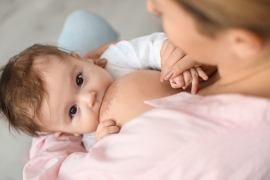 Young woman breastfeeding her baby at home, closeup