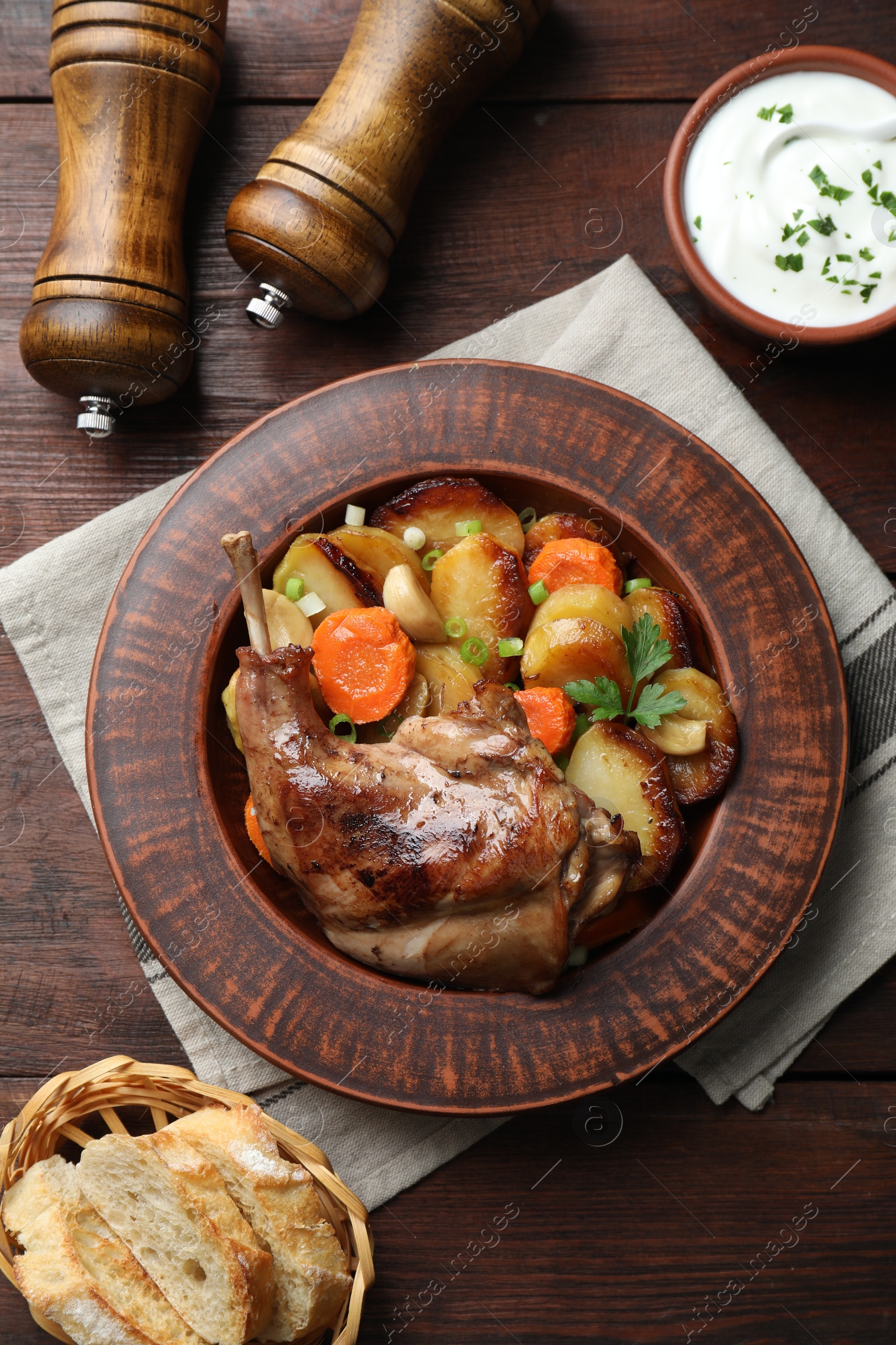 Photo of Tasty cooked rabbit meat with vegetables served on wooden table, flat lay