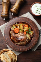 Photo of Tasty cooked rabbit meat with vegetables served on wooden table, flat lay