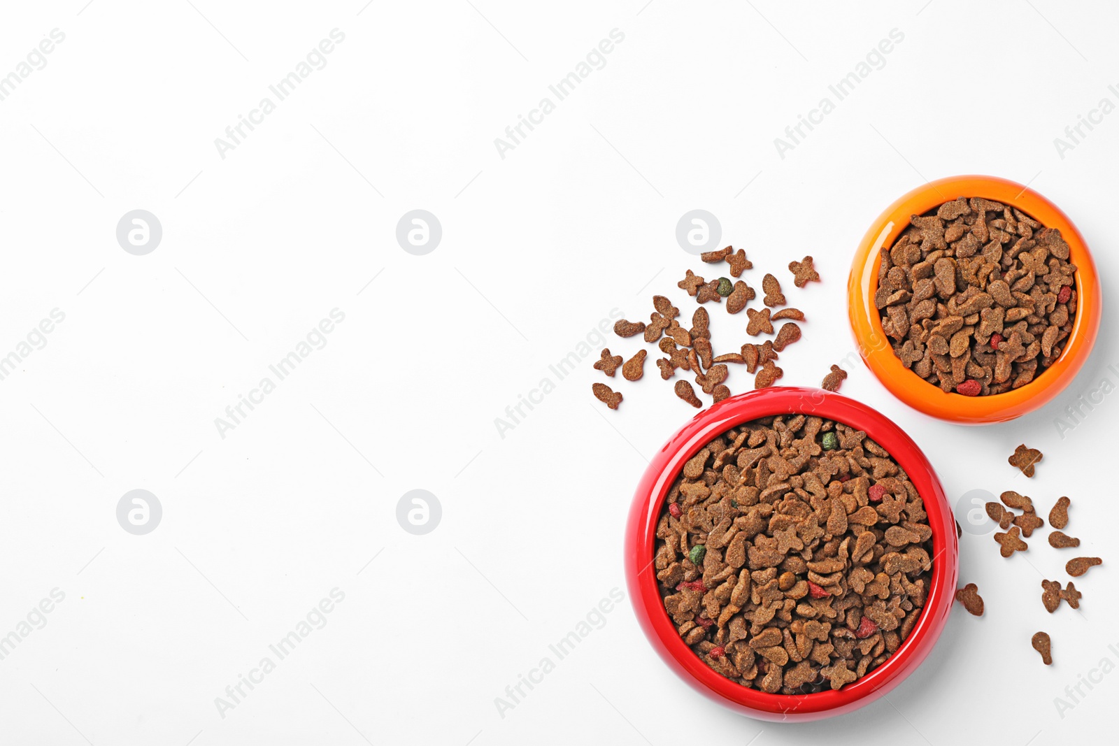 Photo of Bowls of dry pet food on white background, top view