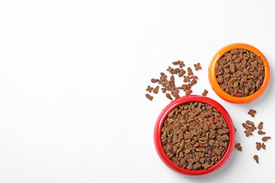 Photo of Bowls of dry pet food on white background, top view