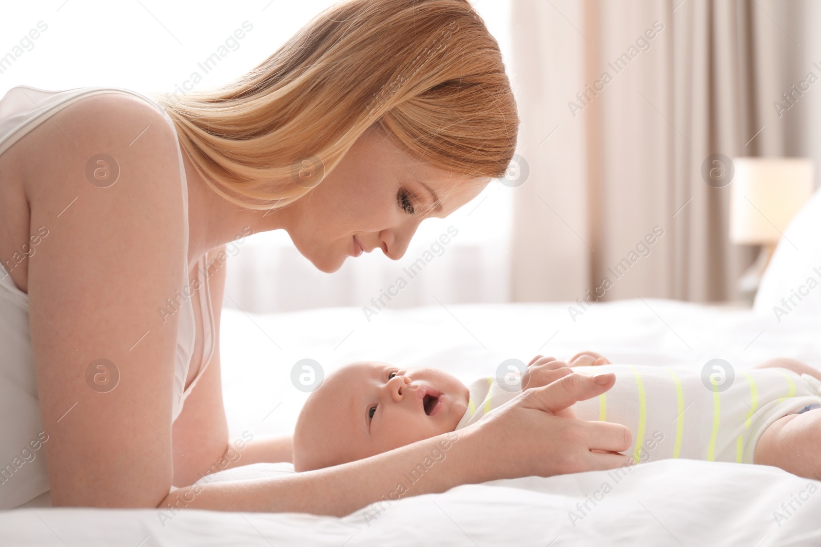 Photo of Mother with her little baby on bed at home