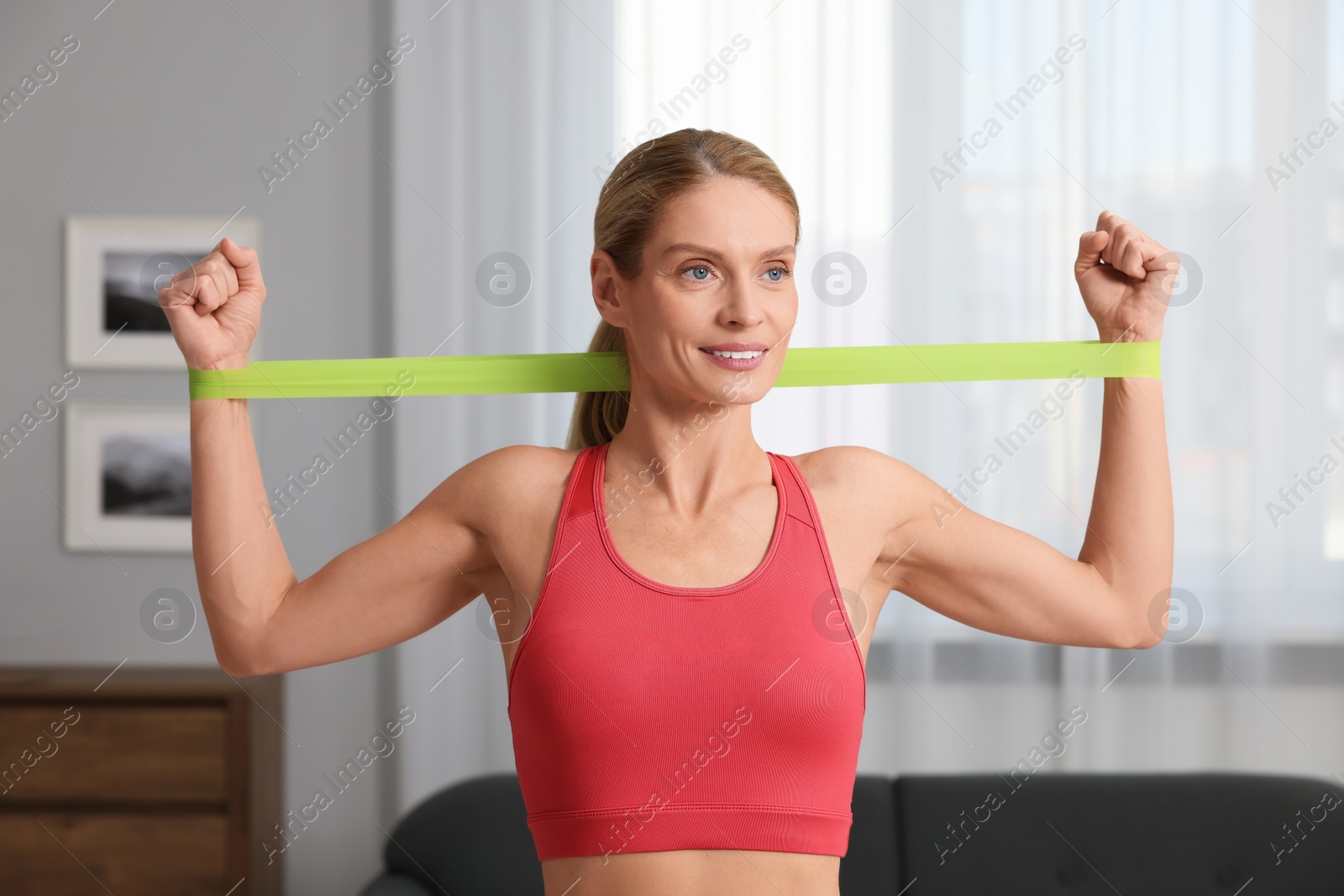 Photo of Athletic woman doing exercise with fitness elastic band at home