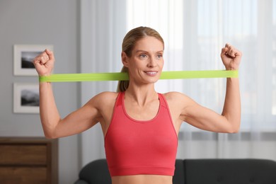 Photo of Athletic woman doing exercise with fitness elastic band at home