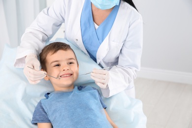 Photo of Dentist examining cute boy's teeth in modern clinic. Space for text