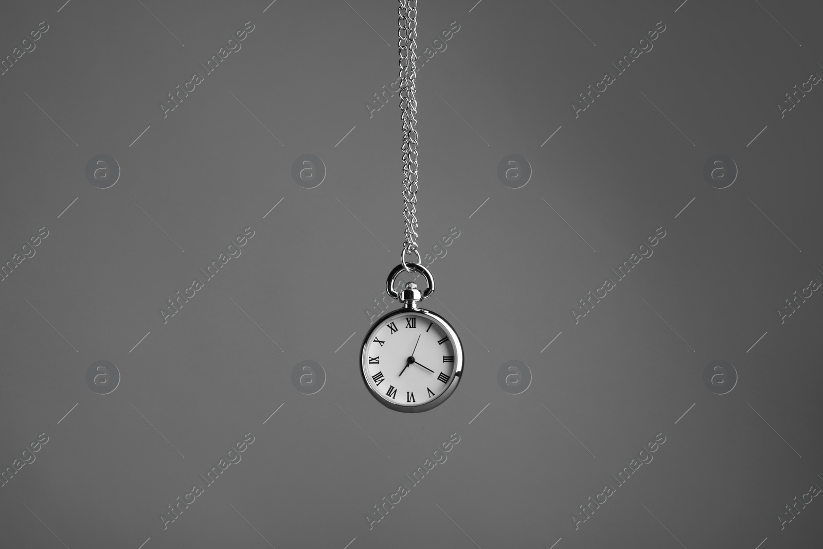 Photo of Stylish pendulum on grey background. Hypnotherapy session