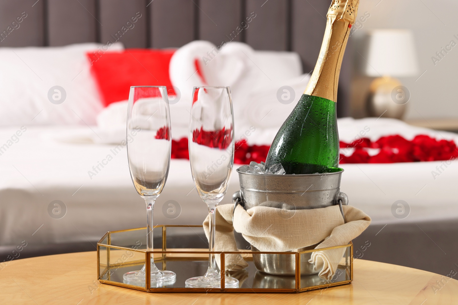 Photo of Honeymoon. Sparkling wine and glasses on wooden table in room