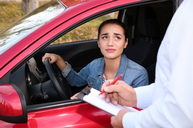 Photo of Instructor near woman in car, outdoors. Passing driving license exam