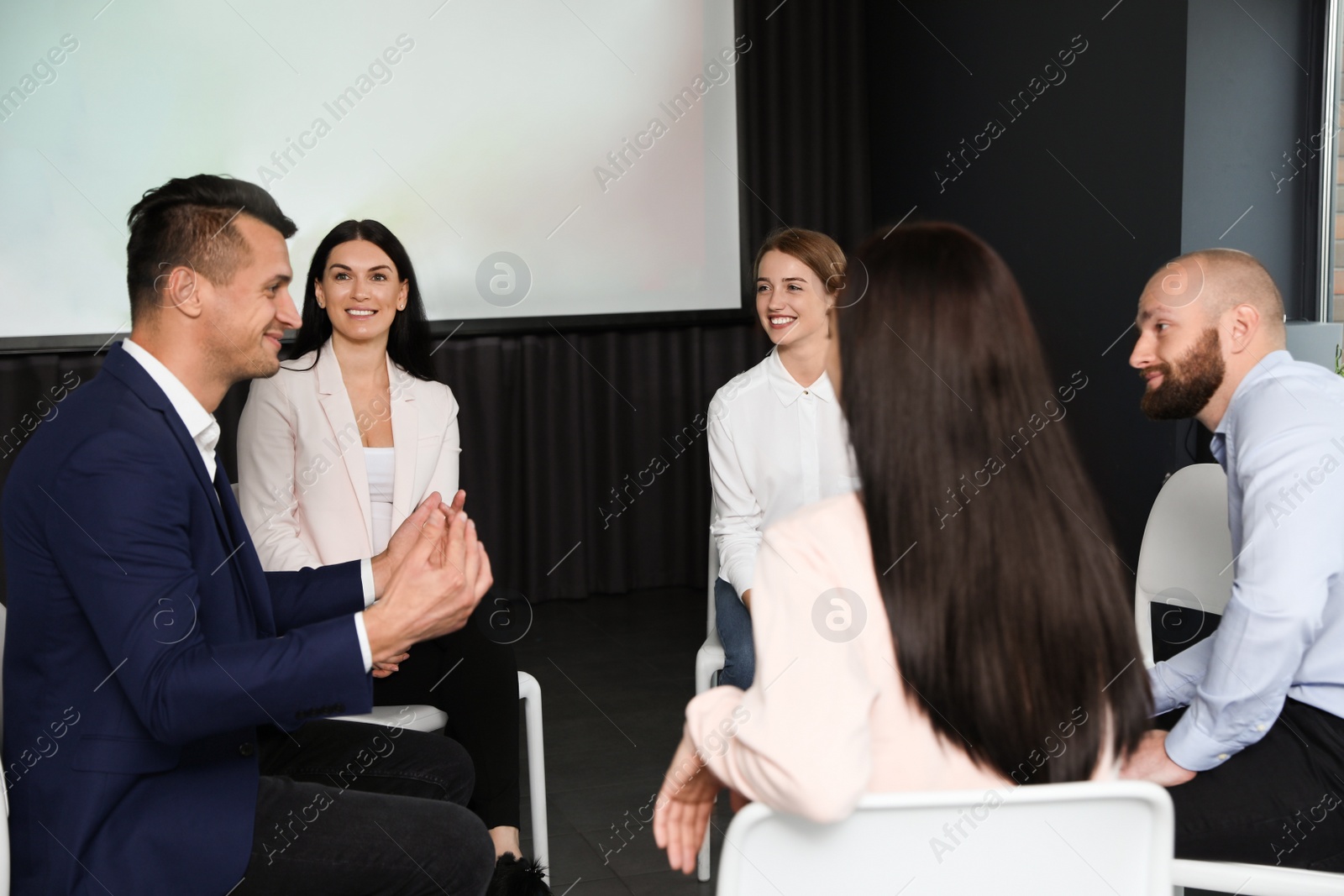 Photo of Business people at seminar in conference room with video projection screen