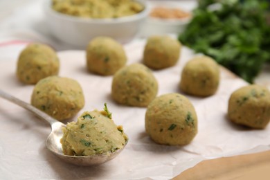 Photo of Raw falafel balls and spoon on parchment, closeup