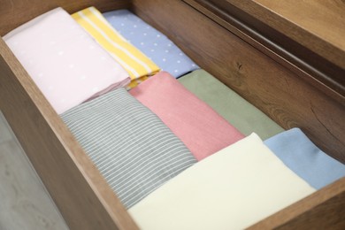 Chest of drawers with different folded clothes, closeup