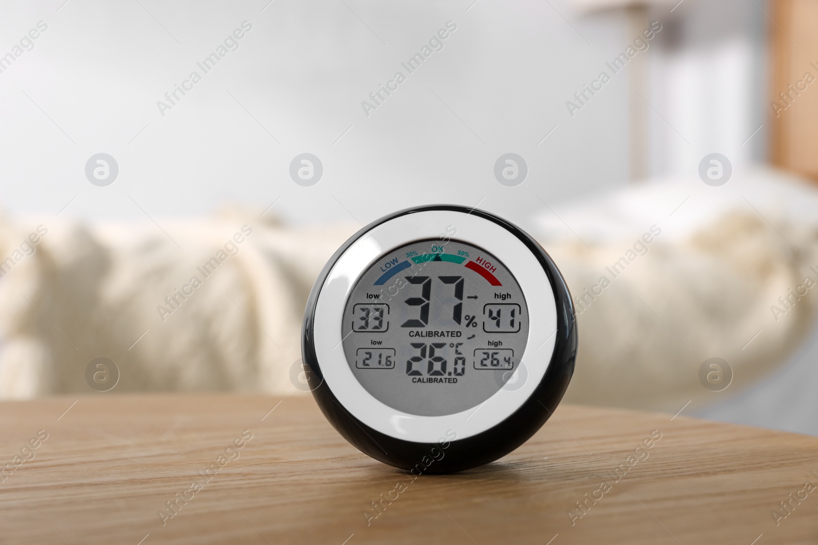 Photo of Digital hygrometer with thermometer on wooden table indoors