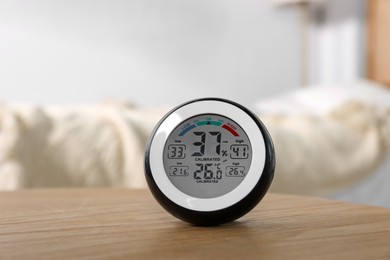 Digital hygrometer with thermometer on wooden table indoors