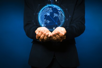 Image of Global innovation. Businessman holding virtual planet on dark blue background, closeup