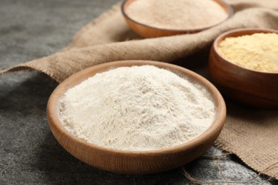 Wooden plate with wheat flour on grey table