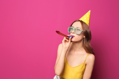 Young woman with party blower on color background. Birthday celebration