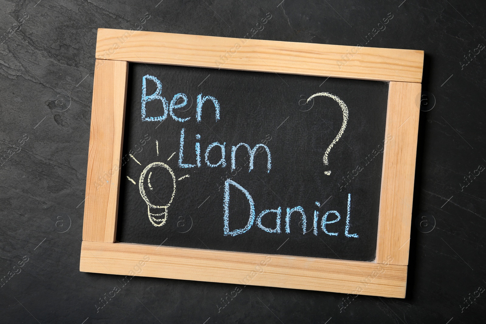 Photo of Blackboard with baby names on black stone table, top view