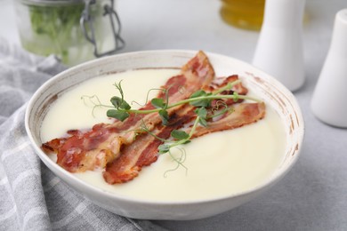 Photo of Delicious potato soup with bacon and microgreens on grey table, closeup