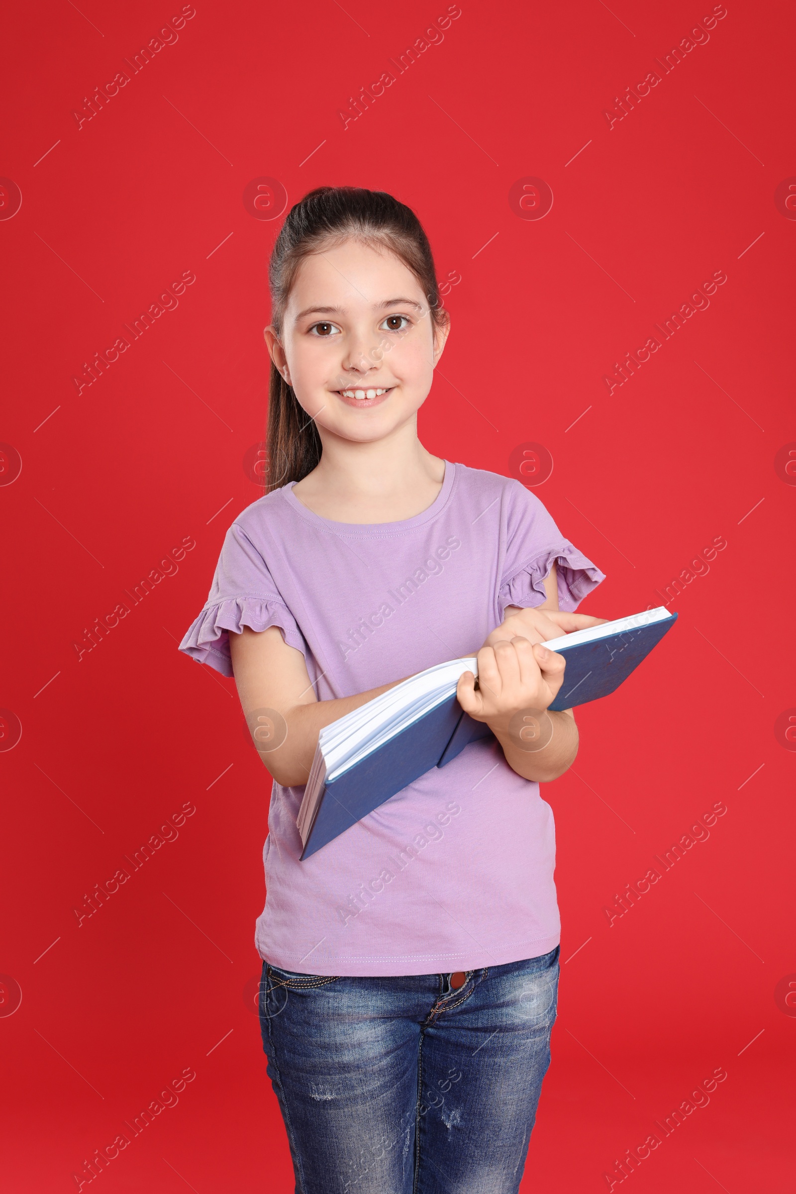 Photo of Cute little girl reading book on color background