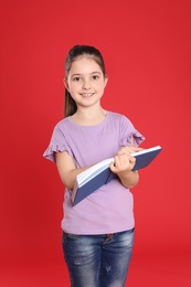 Cute little girl reading book on color background