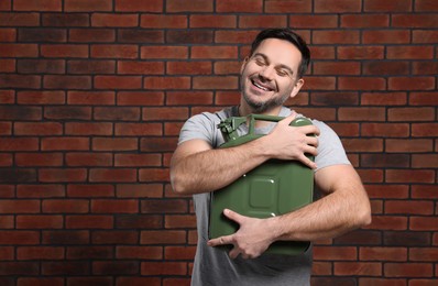 Man holding khaki metal canister against brick wall, space for text