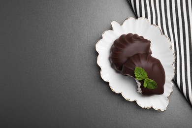 Delicious chocolate covered zephyrs with mint on black table, top view. Space for text