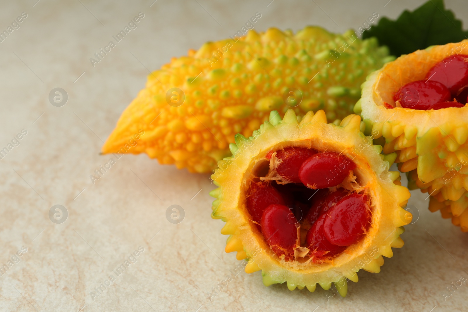 Photo of Fresh bitter melons with red seeds on light table, closeup