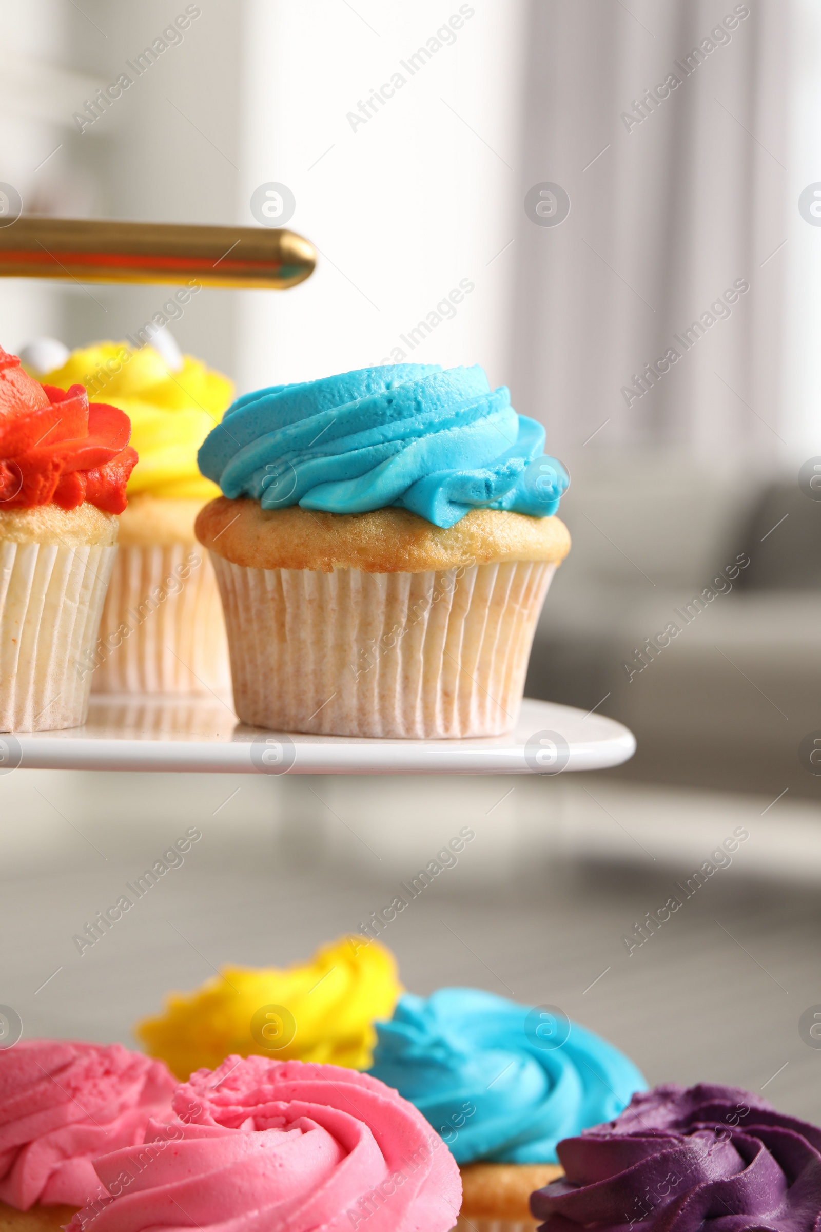 Photo of Delicious cupcakes with bright cream on dessert stand indoors, closeup