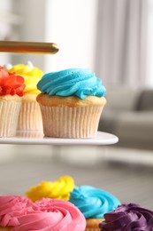 Photo of Delicious cupcakes with bright cream on dessert stand indoors, closeup