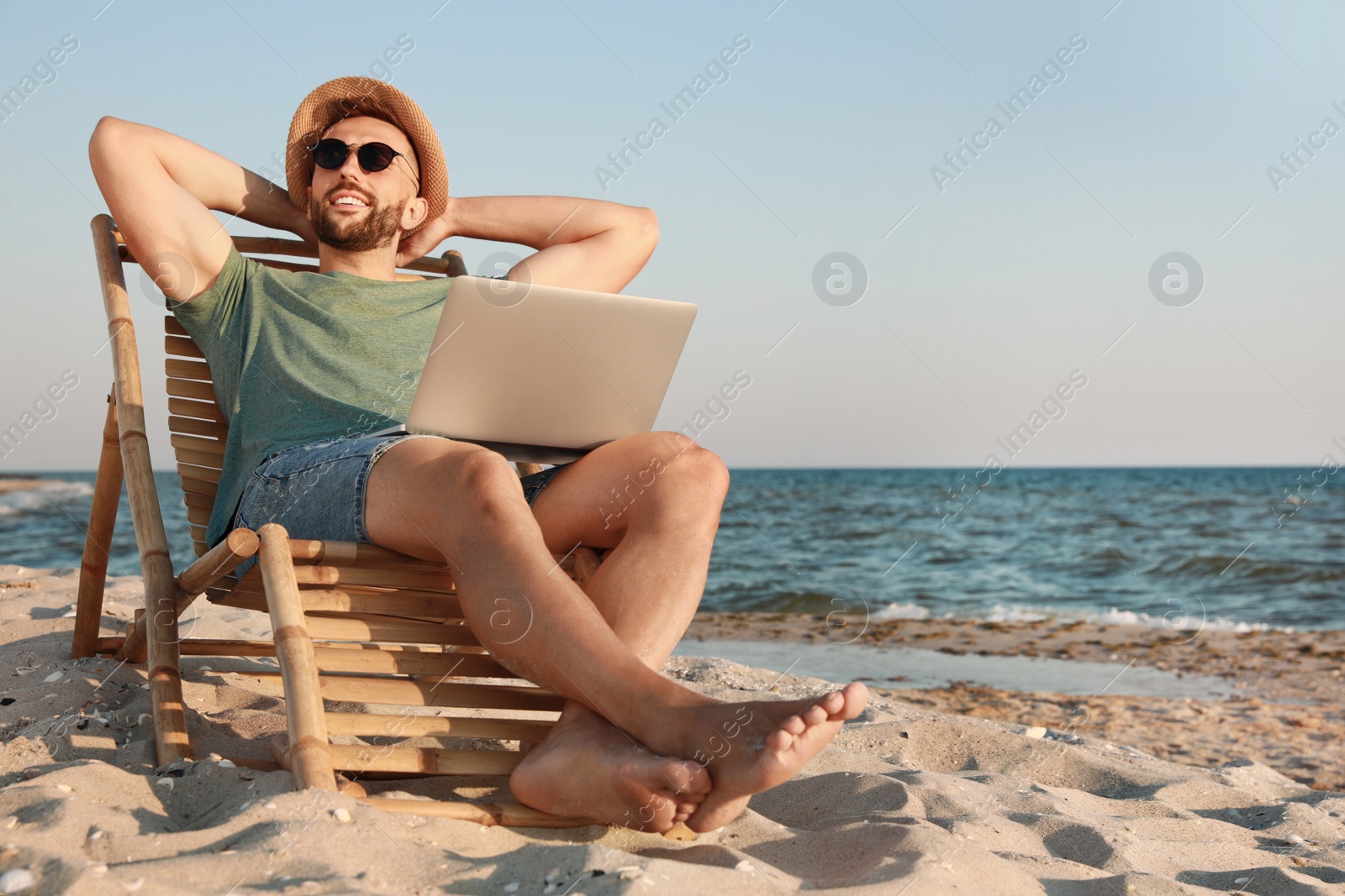 Photo of Man with laptop relaxing in deck chair on beach