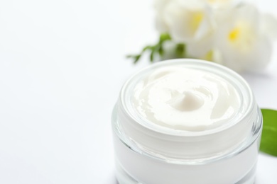 Photo of Jar of cream and flowers on white background. Professional cosmetic products