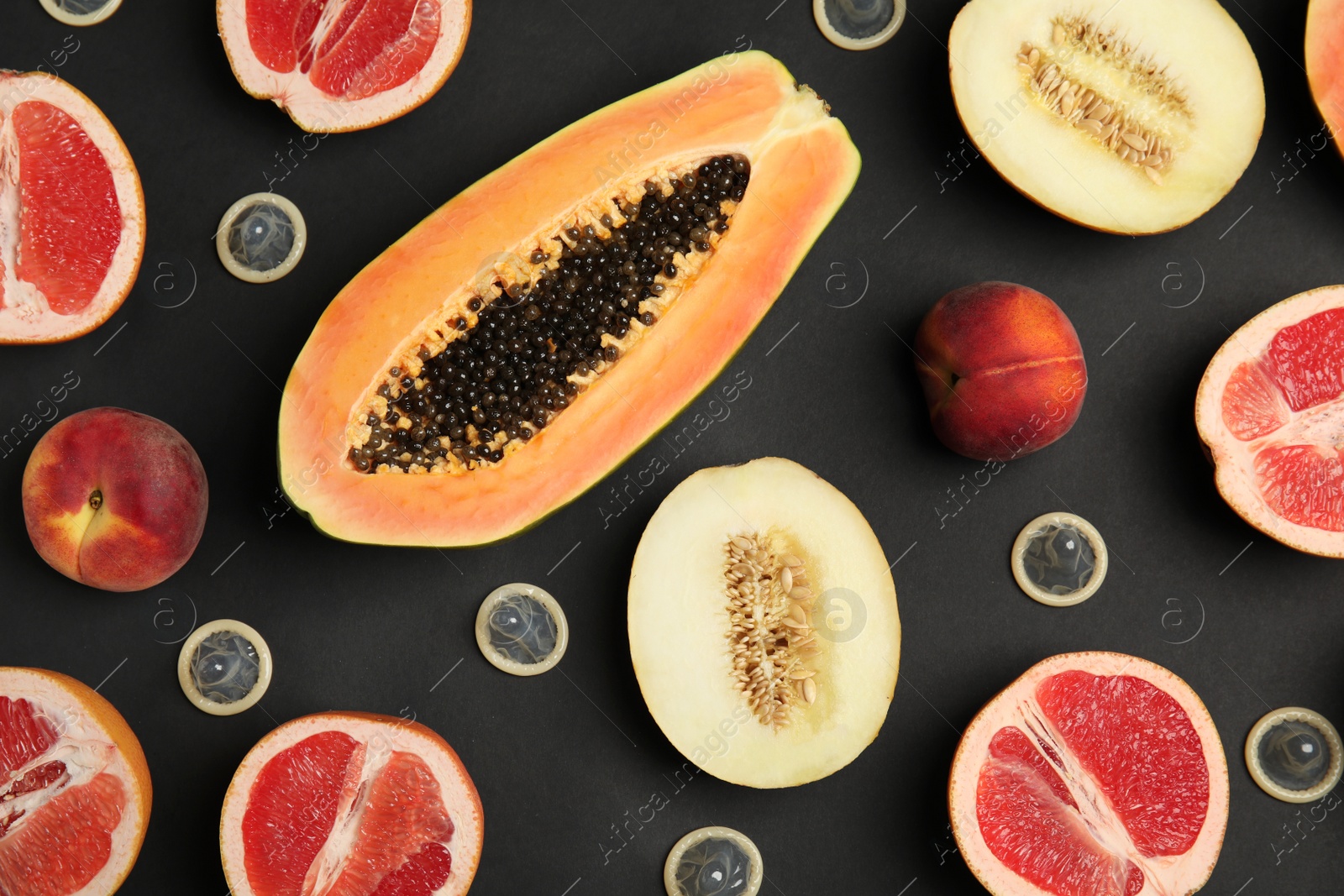 Photo of Flat lay composition with condoms and exotic fruits on black background. Erotic concept