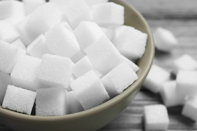 White sugar cubes in bowl on wooden table, closeup