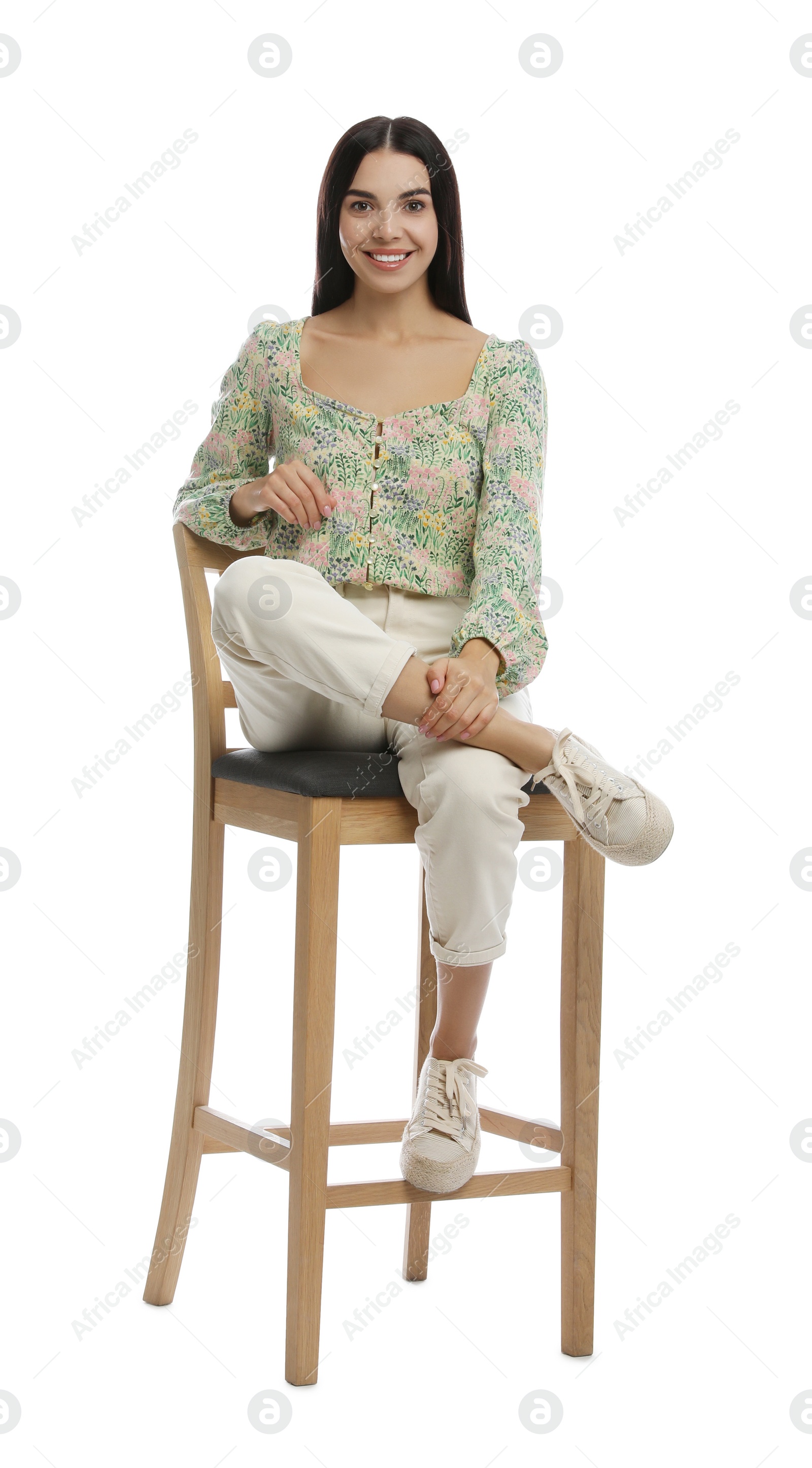 Photo of Beautiful young woman sitting on stool against white background