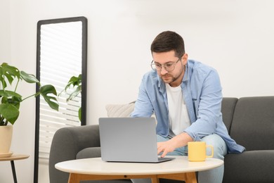 Photo of Man working with laptop at table in living room