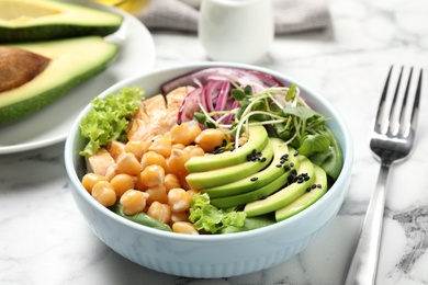 Photo of Delicious avocado salad with chickpea on white marble table