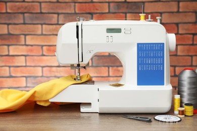 Photo of Sewing machine with fabric and craft accessories on wooden table against brick wall