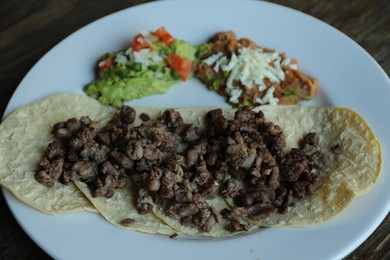 Photo of Plate with delicious tacos on table, closeup