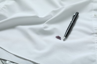 Photo of Pen and stain of black ink on white shirt, closeup. Space for text