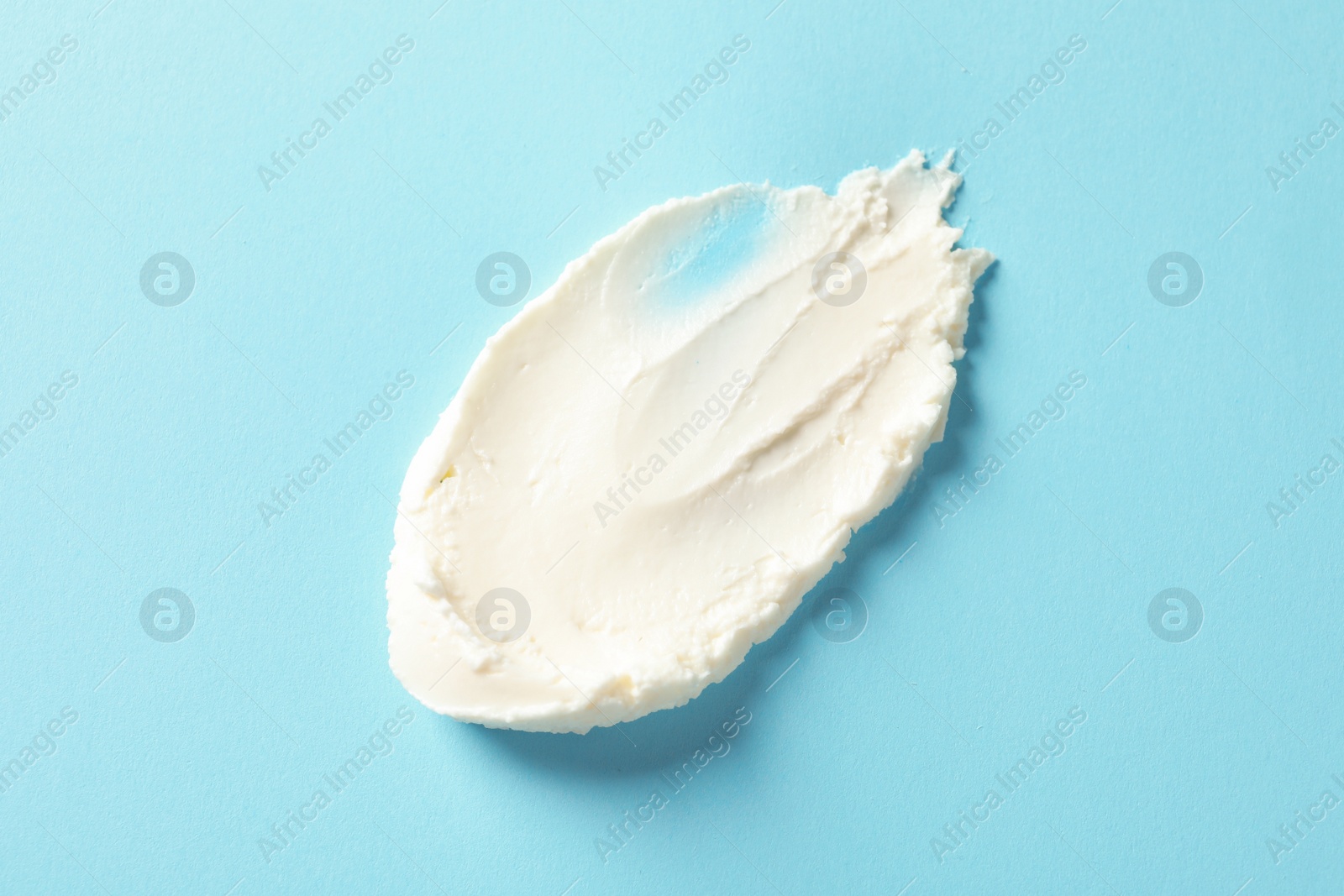 Photo of Smear of tasty cream cheese on color background, top view