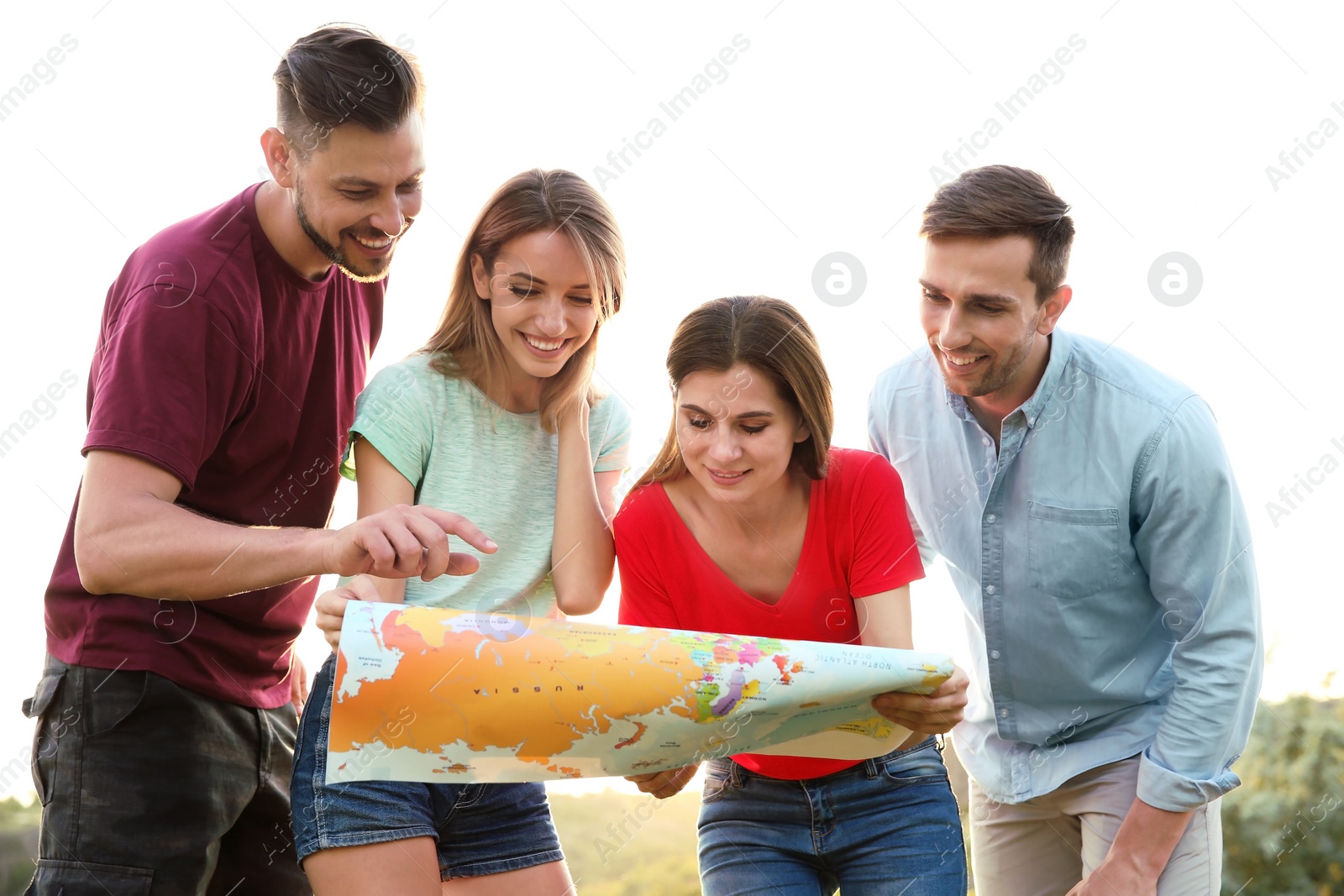 Photo of Group of young people exploring map outdoors. Camping season