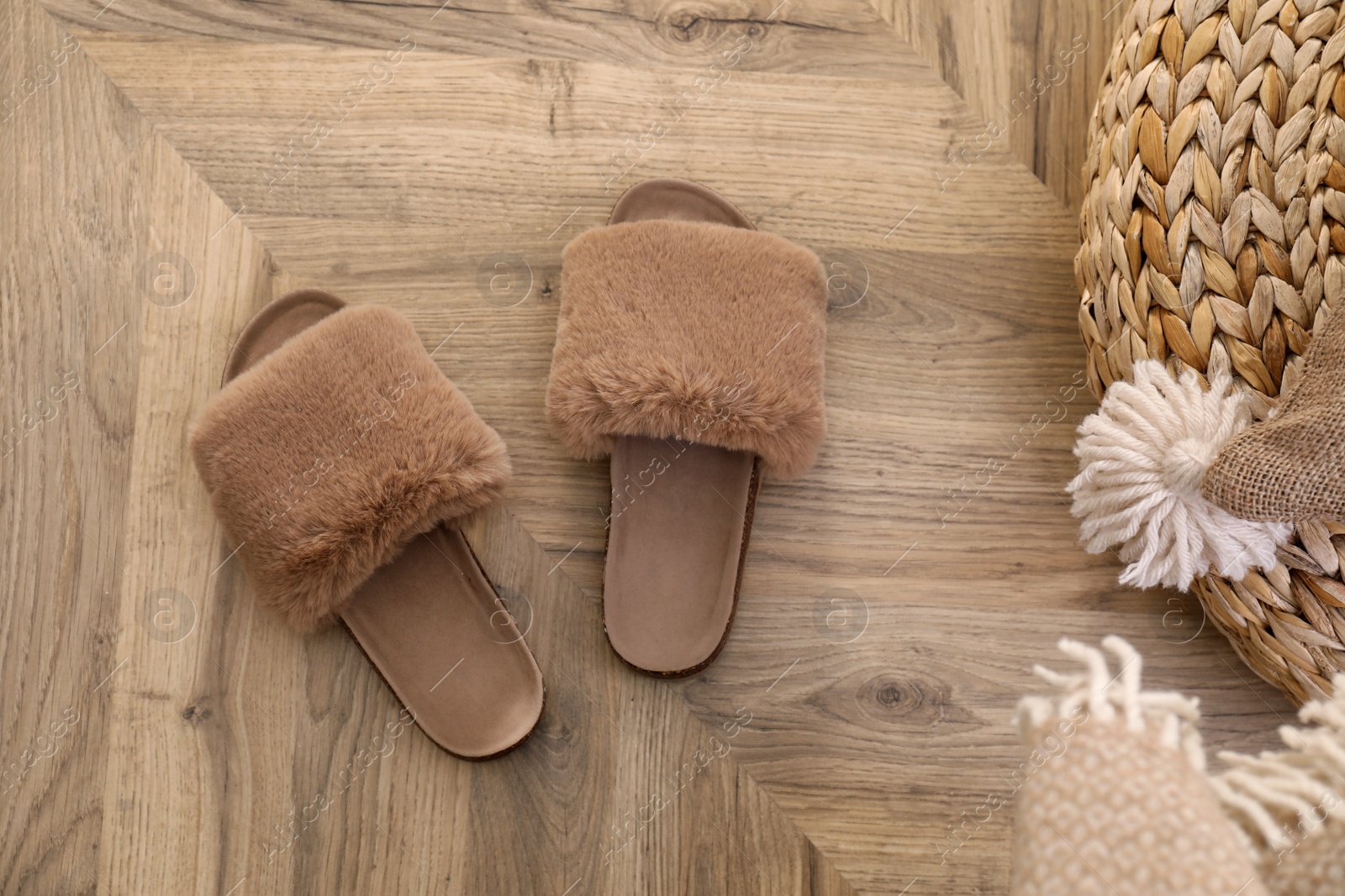 Photo of Brown warm slippers on wooden floor in room, flat lay