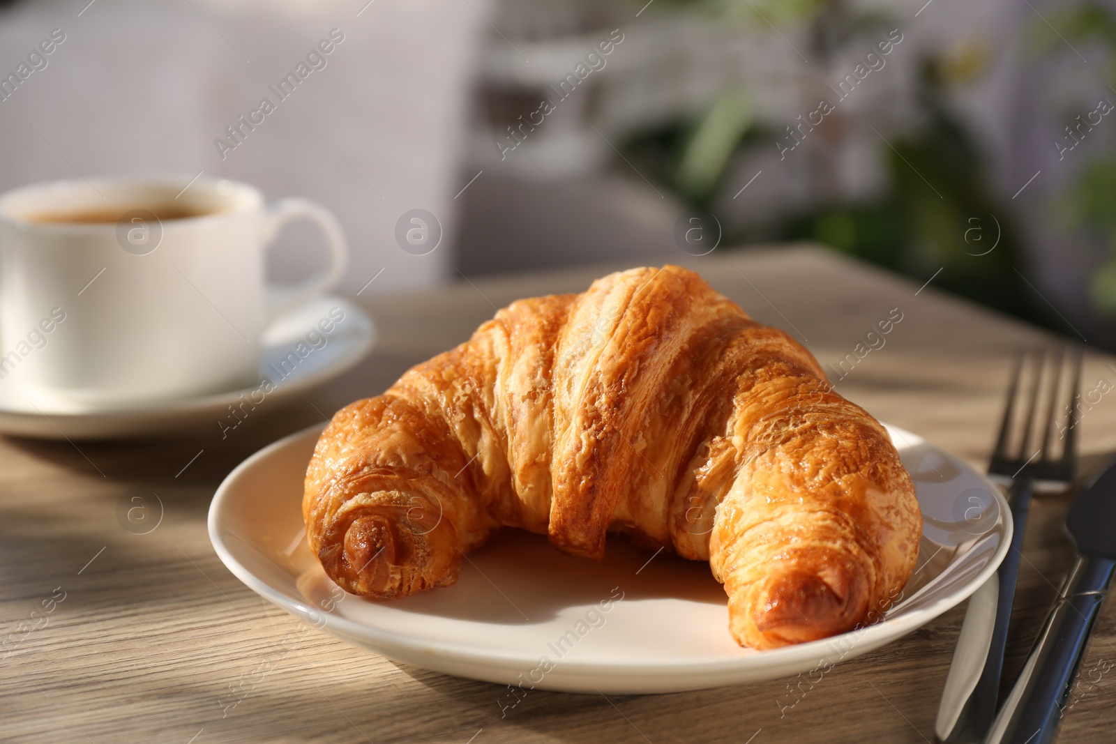 Photo of Delicious fresh croissant served on wooden table, closeup