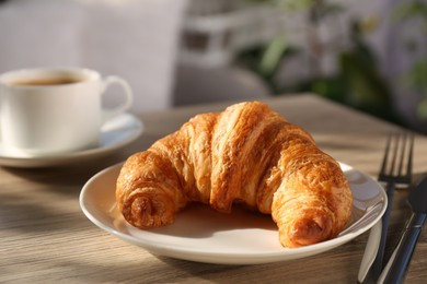 Photo of Delicious fresh croissant served on wooden table, closeup