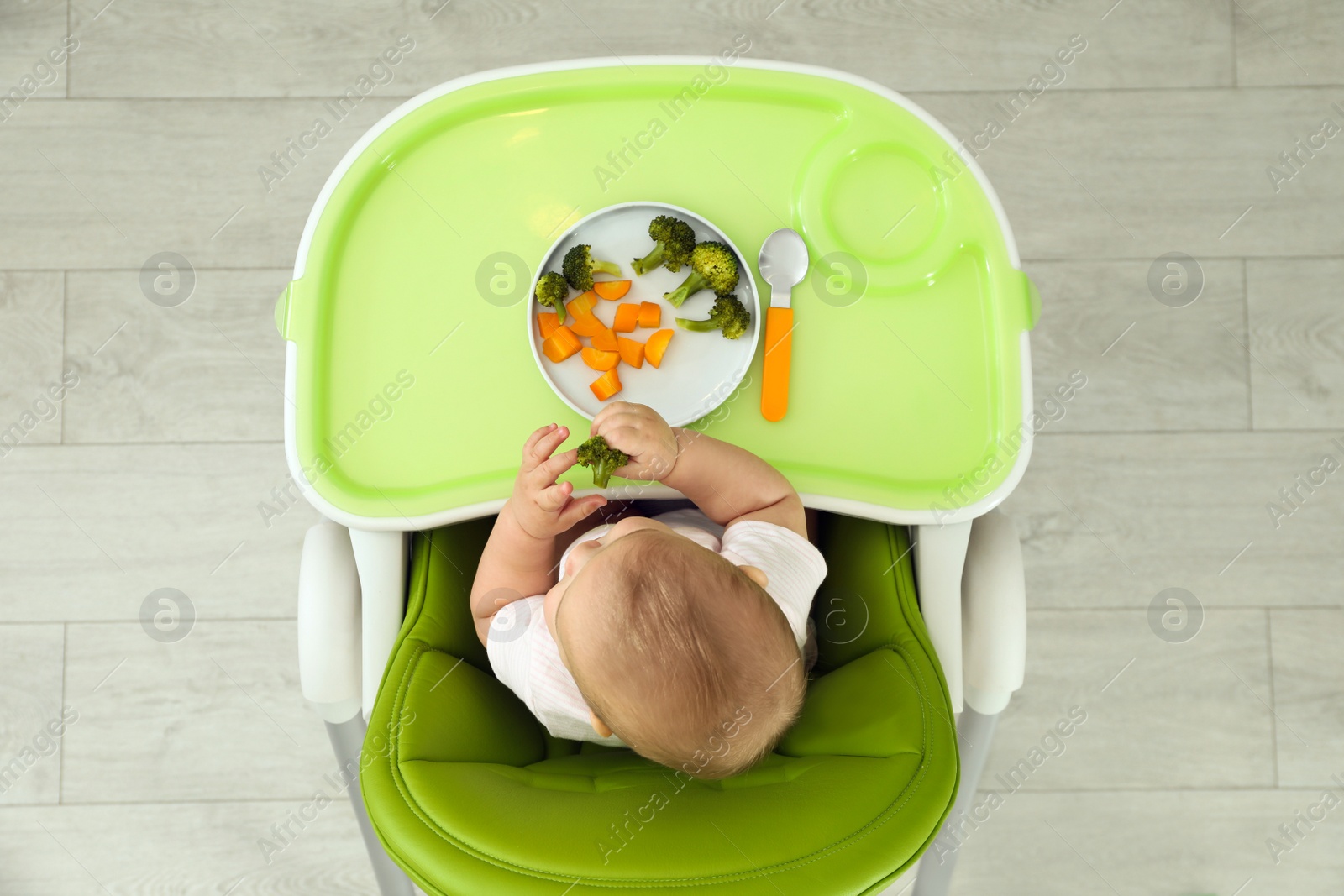 Photo of Cute little baby eating healthy food, top view