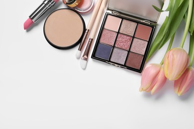 Flat lay composition with different makeup products and beautiful tulips on white background, space for text