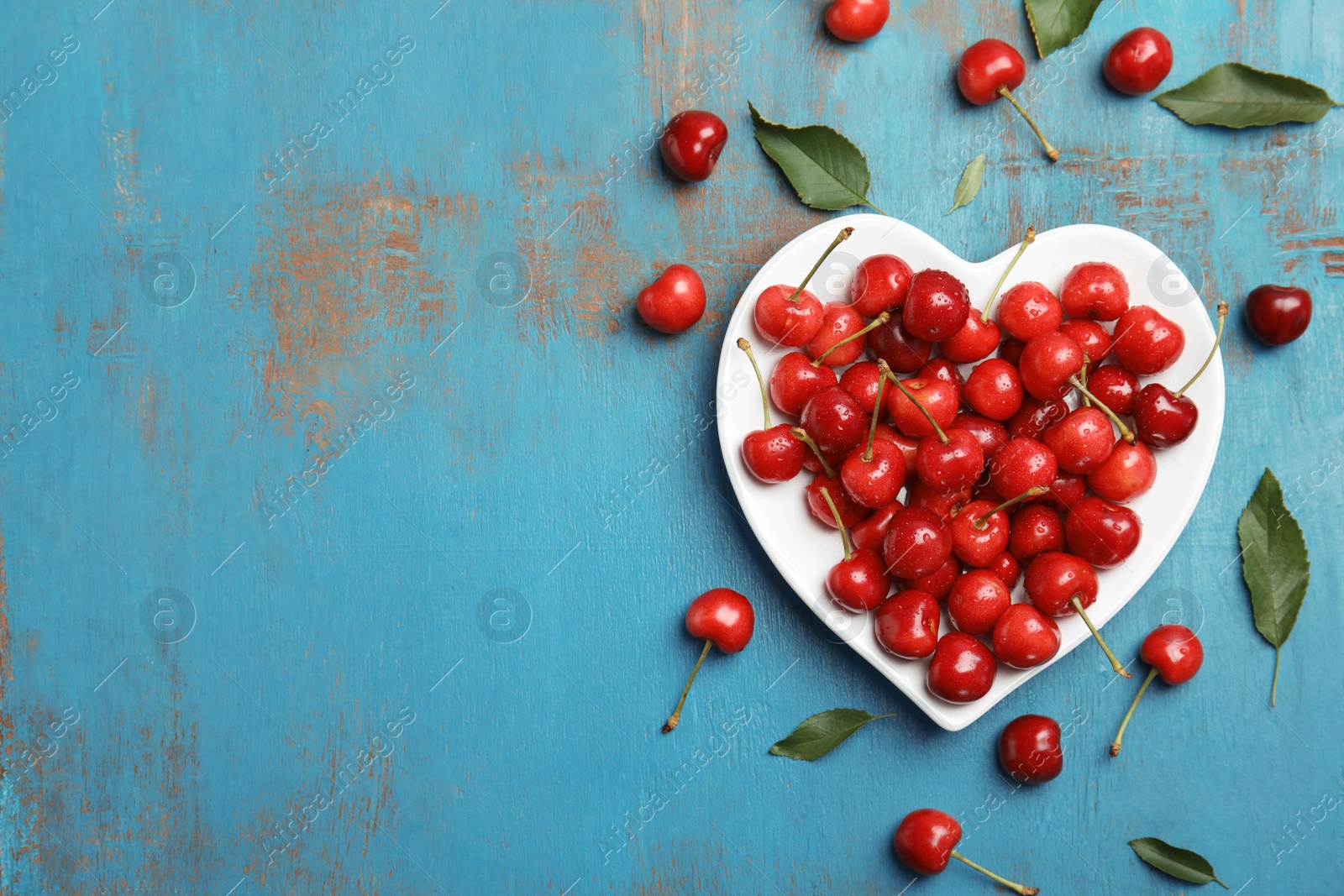 Photo of Heart shaped plate with sweet red cherries on wooden background, top view