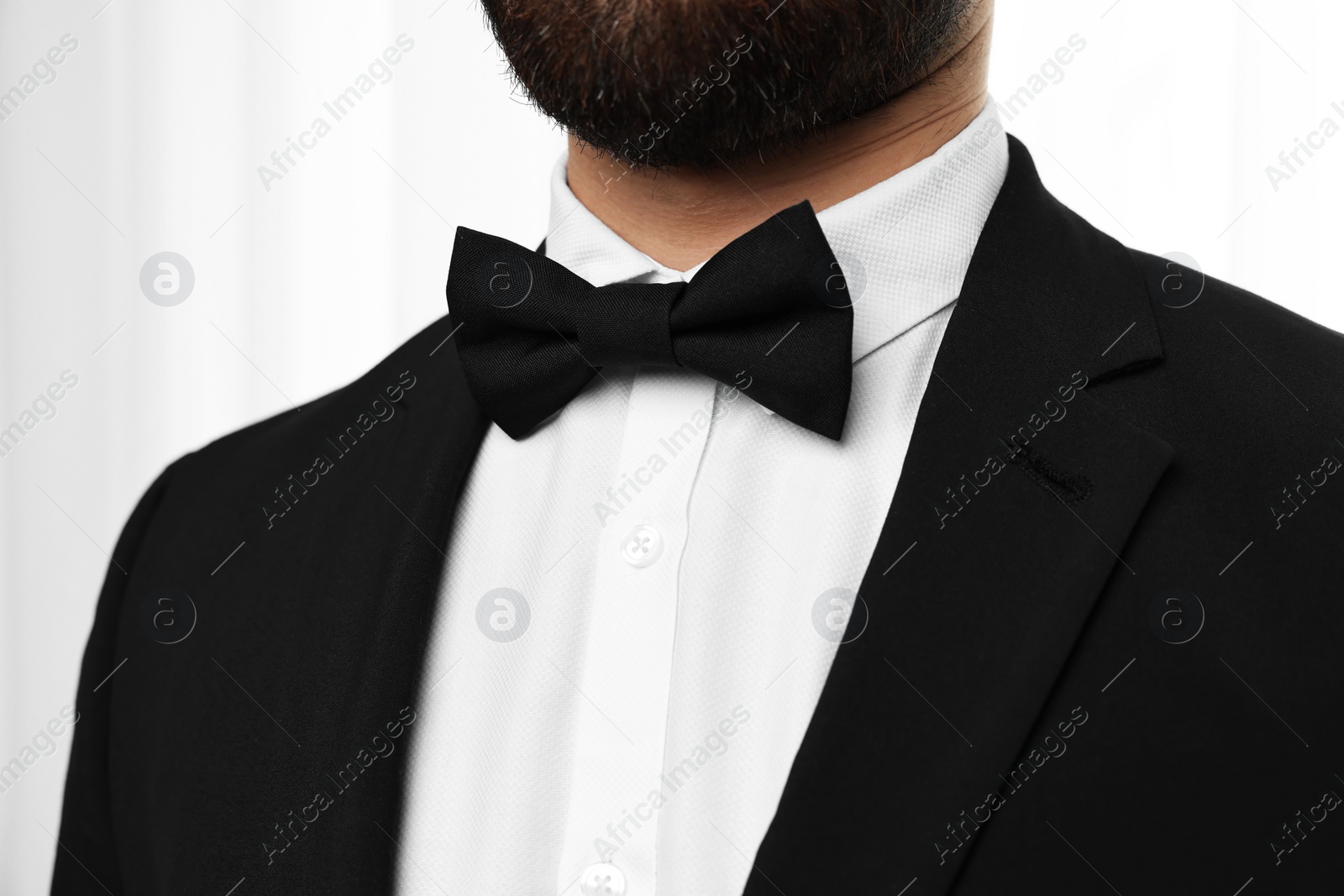 Photo of Man in suit, shirt and bow tie indoors, closeup